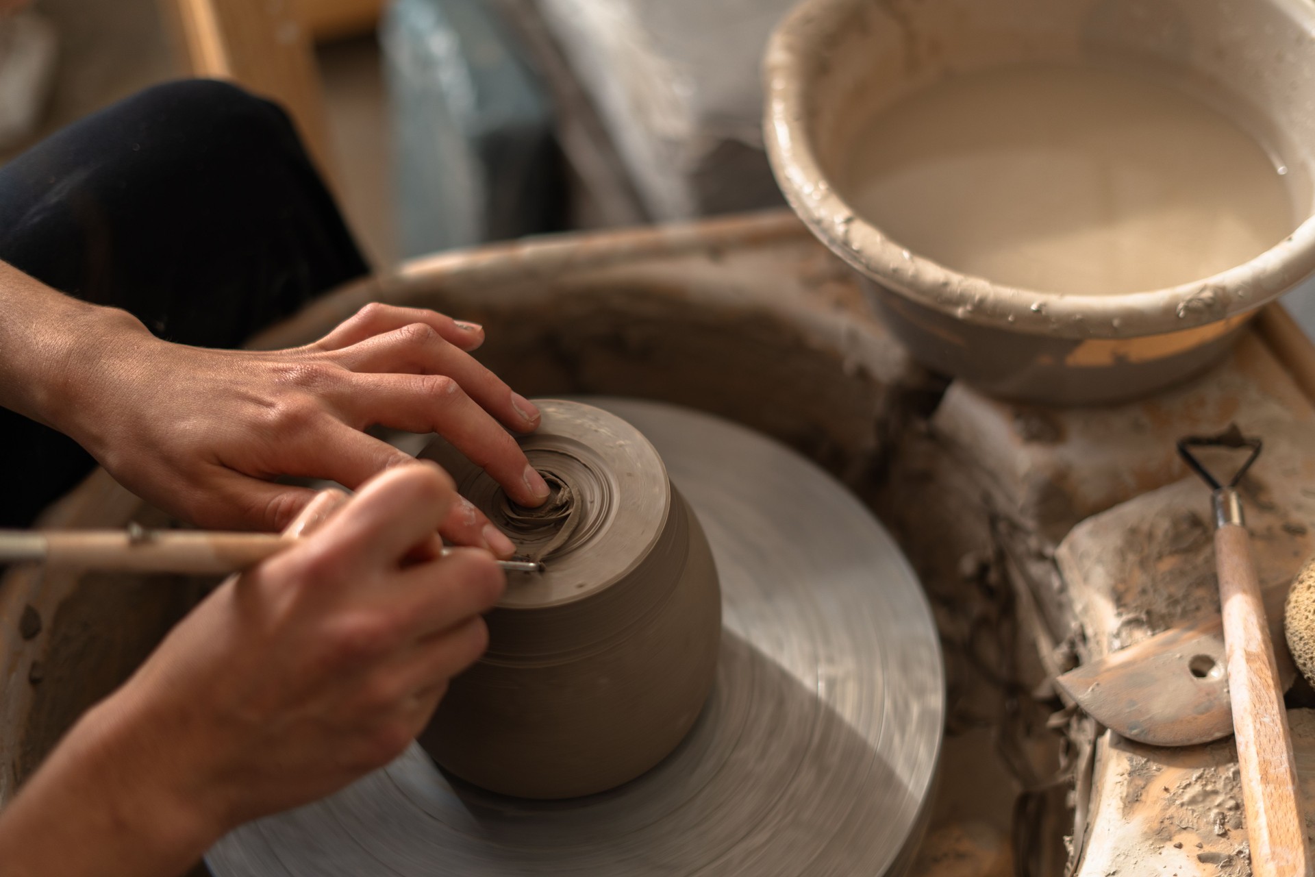 Ceramist using pottery wheel creating clay vessel in workshop