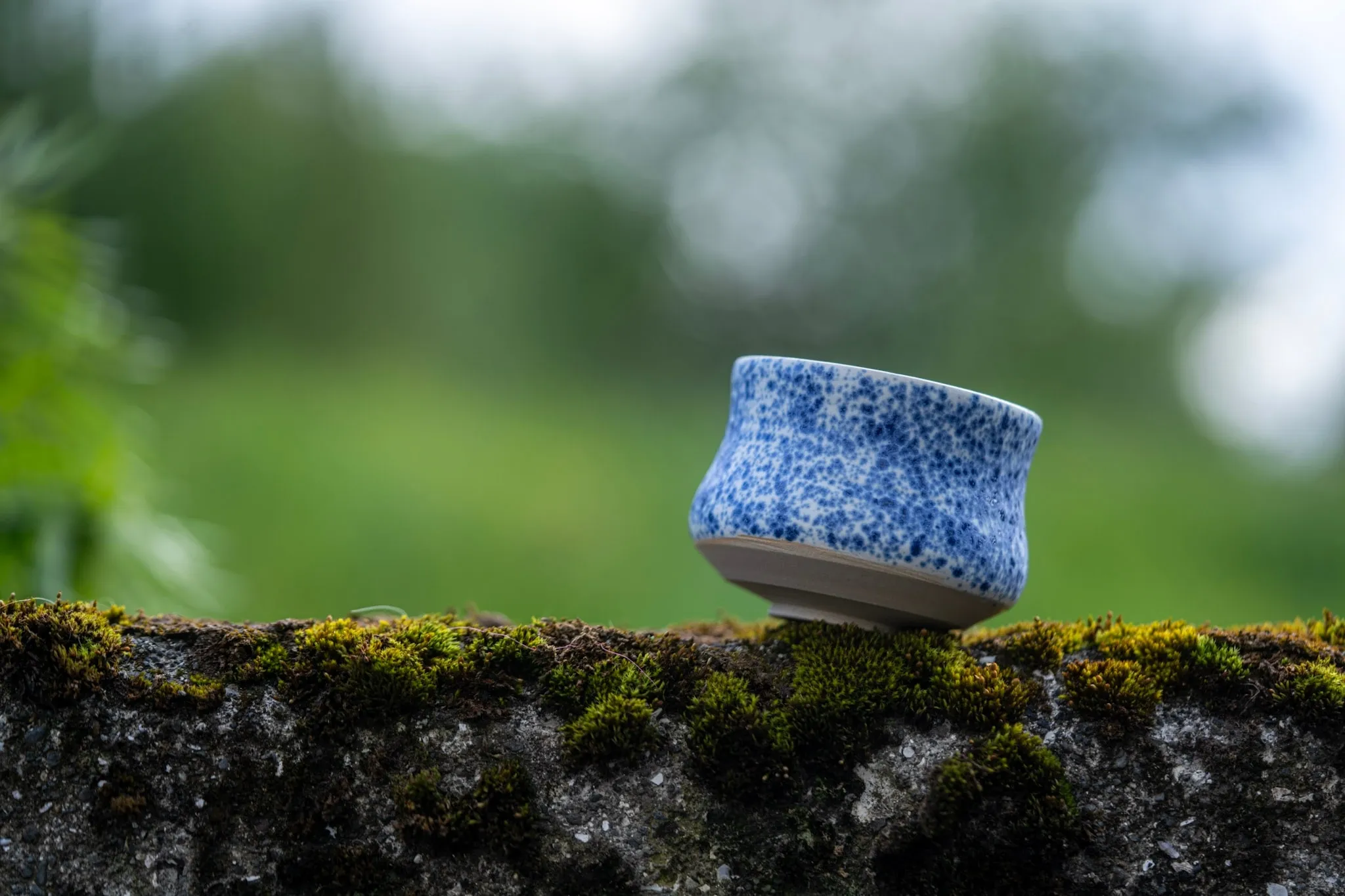 A blue wheel-thrown cup resting on Icelandic moss